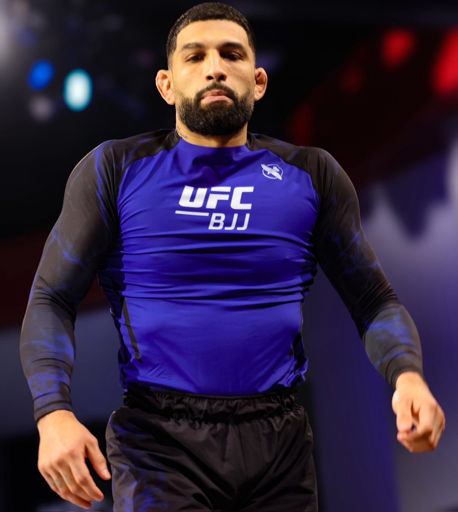 UFC BJJ Athlete Andy Varela in competition rashguard, arena lights glowing behind him