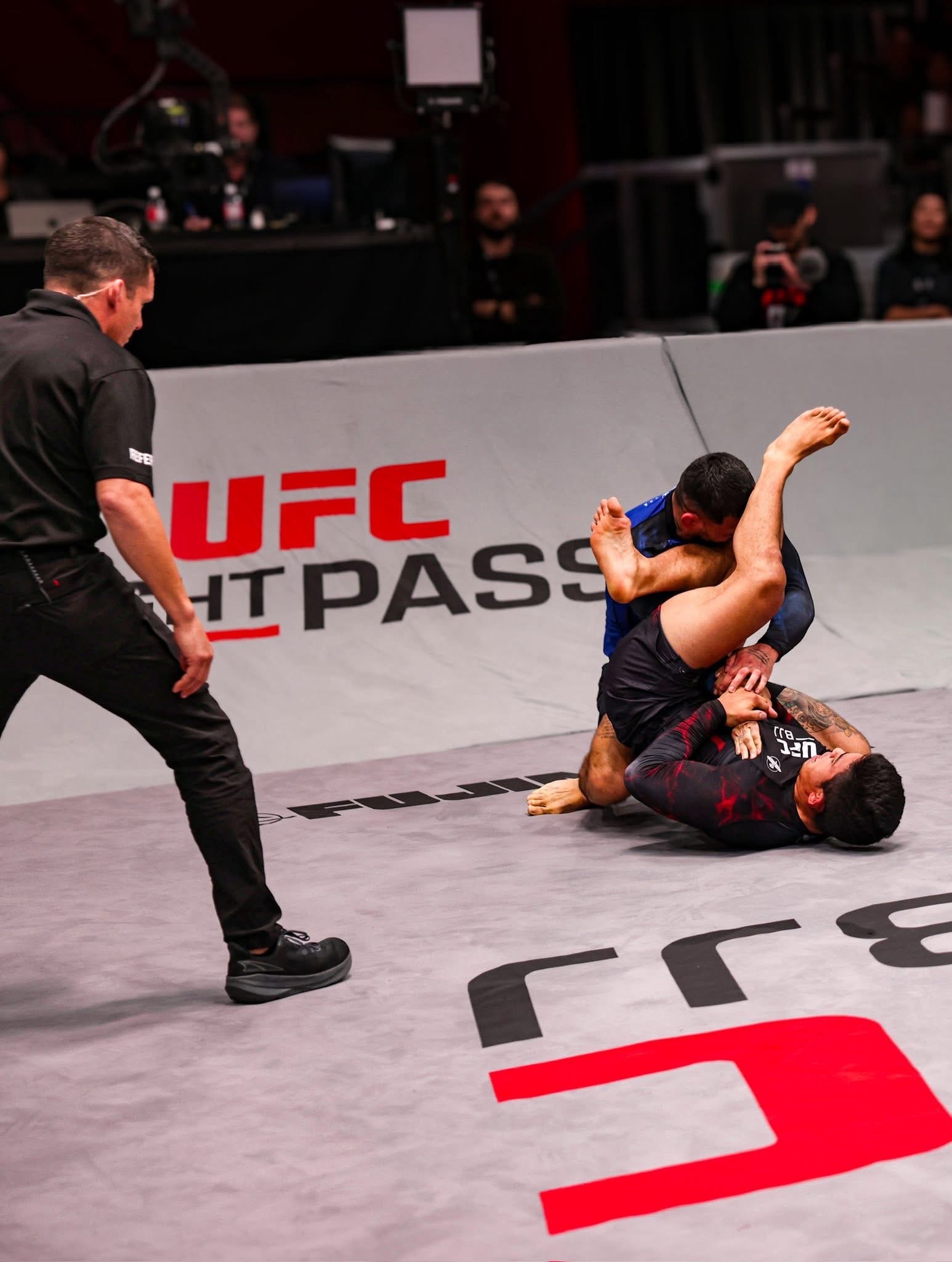 Andy Murasaki applying an armbar submission on the UFC BJJ mat, referee watching closely